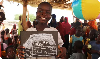glad dreng i en kalsse der holder en tegning med en unicef bygning på